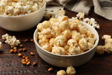 Tasty popcorn and corn kernels on wooden table, closeup