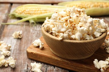 Tasty popcorn and corncobs on wooden table, closeup. Space for text