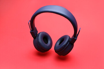 Pair of wireless headphones on coral background