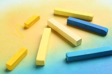 Yellow and light blue chalk pastels on color background, closeup
