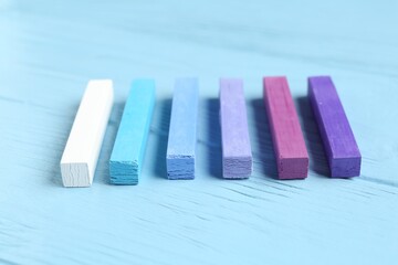 Colorful chalk pastels on light wooden table, closeup