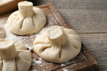 Uncooked khinkalis (dumplings) on wooden table, closeup