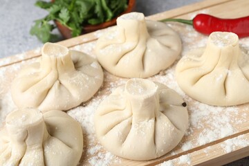 Uncooked khinkalis (dumplings), chili pepper and parsley on table, closeup