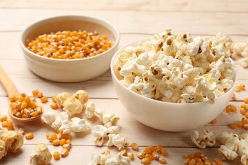 Tasty popcorn and corn kernels on white wooden table, closeup