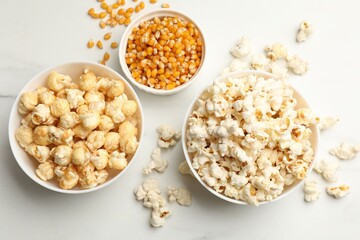 Tasty popcorn and corn kernels on white table, flat lay