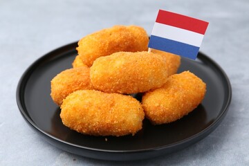 Delicious fried croquettes and flag of Netherlands on gray table, closeup