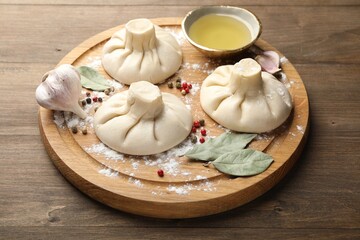 Uncooked khinkalis (dumplings) with peppercorns, flour and bay leaves on wooden table