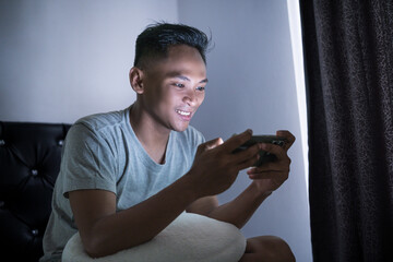 A cheerful individual enjoying a mobile gaming experience in a cozy indoor setting, illuminated by...