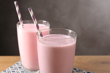 Tasty milkshakes in glasses on wooden table, closeup. Space for text