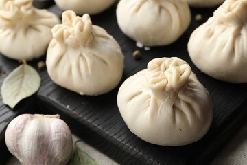 Uncooked khinkalis (dumplings) with peppercorns, garlic and bay leaves on table, closeup