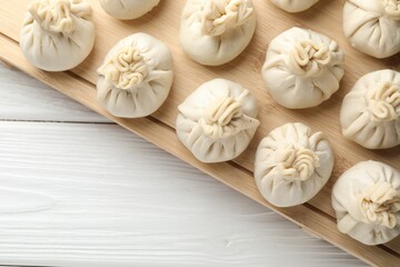 Uncooked khinkalis (dumplings) on white wooden table, top view. Space for text