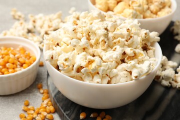 Tasty popcorn and corn kernels on light grey table, closeup