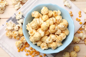 Tasty popcorn and corn kernels on light wooden table, flat lay