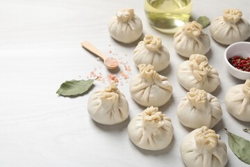 Uncooked khinkalis (dumplings) and spices on white wooden table, closeup. Space for text