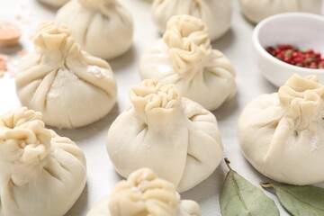 Uncooked khinkalis (dumplings) and spices on white wooden table, closeup