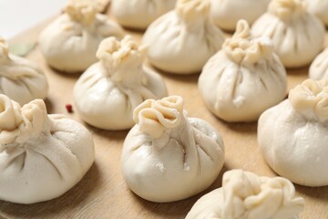 Many uncooked khinkalis (dumplings) on table, closeup