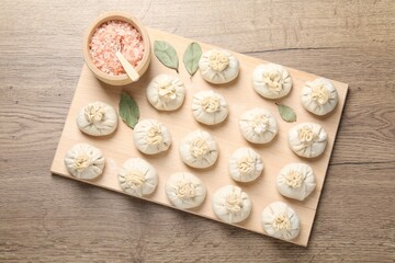 Uncooked khinkalis (dumplings) and spices on wooden table, top view