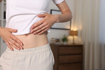 Fototapeta na wymiar Woman with flat belly at home, closeup. Space for text