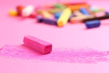Many colorful chalk pastels on pink background, closeup