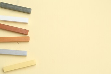 Many colorful chalk pastels on beige background, flat lay. Space for text