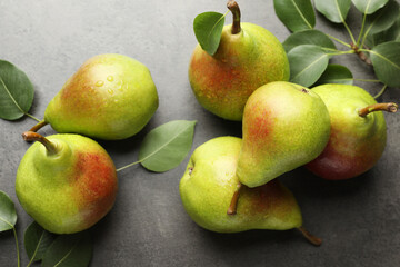 Fresh ripe pears and green leaves on grey table, flat lay