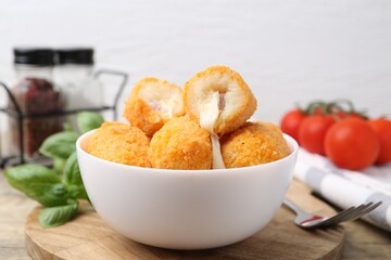 Delicious fried croquettes in bowl, tomatoes and spices on table, closeup