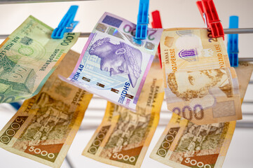 Conceptual image of Albanian lek currency banknotes hanging on a portable clothes drying rack with clothespins. Symbolizing money laundering, black cash, financial fraud, tax evasion, corruption. 