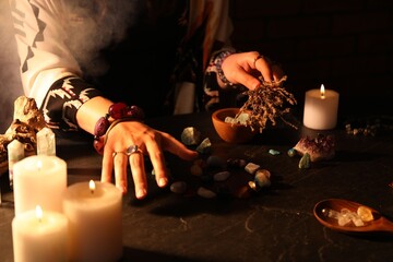 Woman doing ritual with healing stones at dark table, closeup