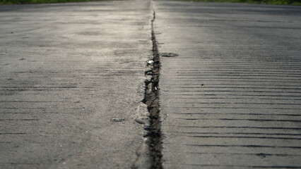 A large, long crack in the concrete road. Earthquake concept photo. This picture has selective focus.