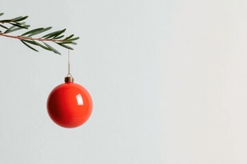 Bright red ornament hangs delicately from evergreen branch again