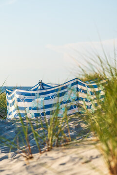 Ein blau-wei&szlig; gestreifter Sichtschutz zwischen Gr&auml;sern an einem Strand im Sommer