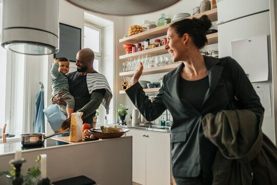 Happy woman waving at son while leaving for work at home