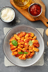 Traditional Italian potato gnocchi with tomato sauce, parmesan cheese and fresh basil leaves on a gray background, top view	