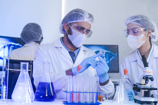 A team of scientists in a high-tech lab collaborates on genetic and medical research. They use microscopes and test tubes to analyze samples for a new discovery.