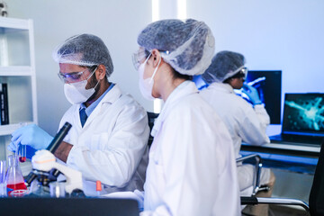 A team of scientists in a high-tech lab collaborates on genetic and medical research. They use microscopes and test tubes to analyze samples for a new discovery.