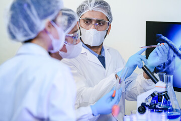 scientists in protective masks and goggles work closely together in a research lab. The focused team collaborates on a medical or biological experiment with great precision.