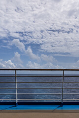 Beautiful ocean horizon view from cruise ship deck calm seas and whimsical cloudscape on bright day, Vertical image.
