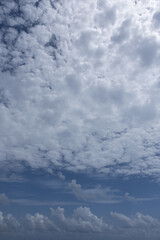 Vertical image of multiple cloud types cloudscape back lit by sun on beautiful day.