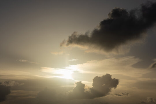Image of dramatic cloudscape gray dark fluffy clouds bright sun rays at sunset