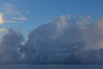 Cloudscape image of partly cloudy sky above large cumulonimbus high altitude clouds background texture