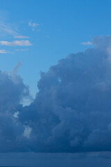 Vertical vivid blue cloudscape partly cloudy sky above large cumulonimbus clouds