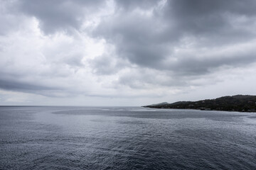 Ocean horizon small piece of land dramatic grayish cloudscape background image