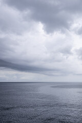 Gray calm ocean horizon and gloomy cloudscape image taken on cruise ship in the Western Caribbean Sea