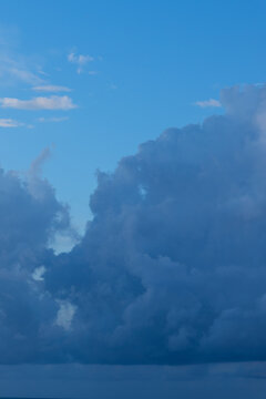 Vertical vivid blue cloudscape partly cloudy sky above large cumulonimbus clouds