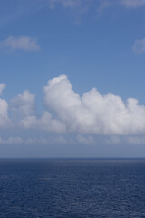 Beautiful vivid vertical photo of whimsy fluffy clouds and open ocean horizon on bright day 