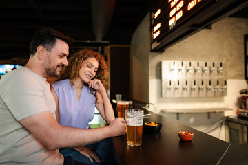 Couple enjoying beer and snacks at the counter in a brewery