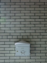White mailbox mounted on a brick wall, simple urban detail with minimalist background.