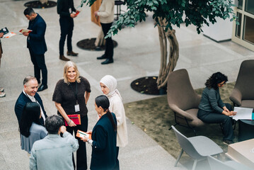 High angle view of male and female corporate business professionals interacting with each other in convention center