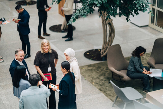 High angle view of male and female corporate business professionals interacting with each other in convention center