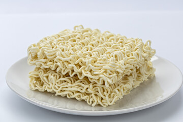Uncooked instant noodle dry ramen block wavy pasta square brick white plate simple food closeup studio lighting minimal style beige color fill calm mood with clean composition and soft texture
